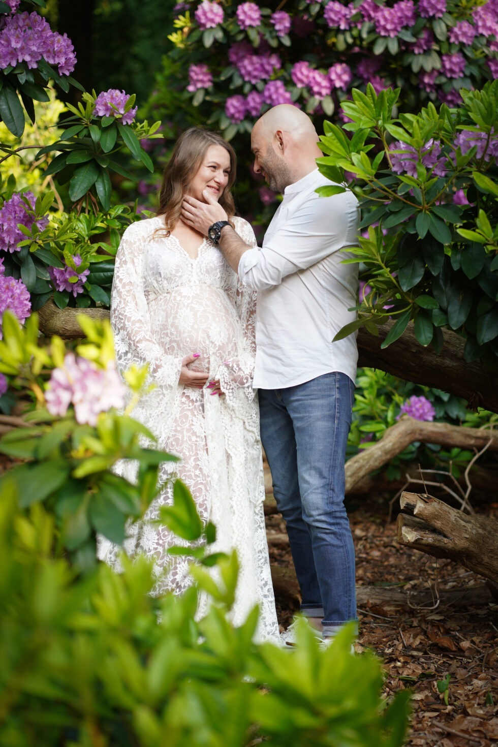 Een stel staat samen in een tuin, met de vrouw in een witte jurk.