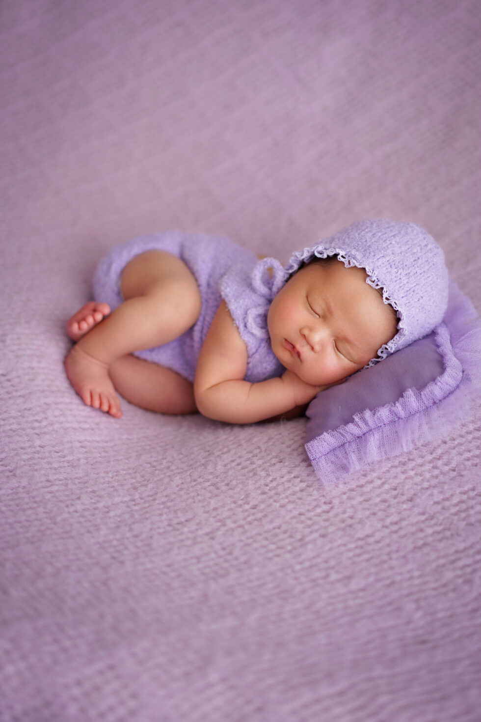 Pasgeboren baby gewikkeld in een paarse doek, vredig slapend op een bijpassende paarse deken.