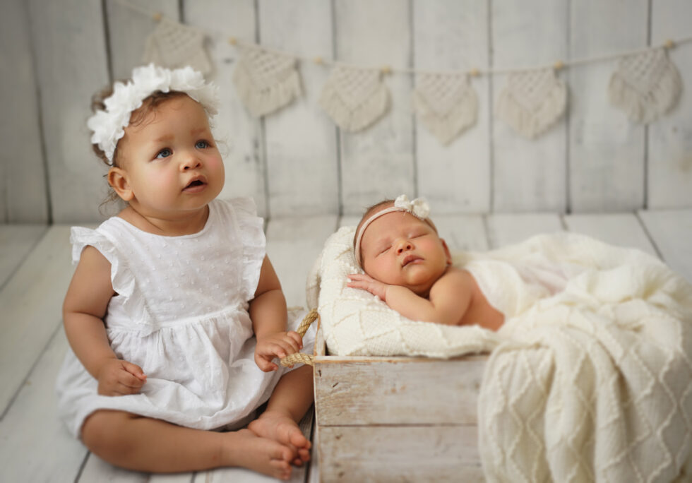 Pasgeboren meisje gekleed in roze kant, liggend op haar zij in een met bloemen versierde setting.