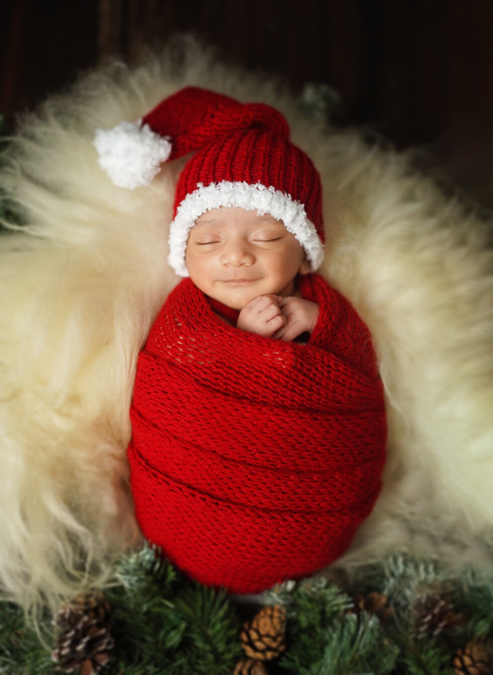 Pasgeboren baby gewikkeld in een donkerrode doek, die vredig slaapt op een crèmekleurige deken